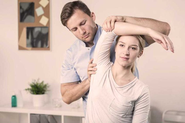 Therapeut mobilisiert das Schultergelenk einer Patientin